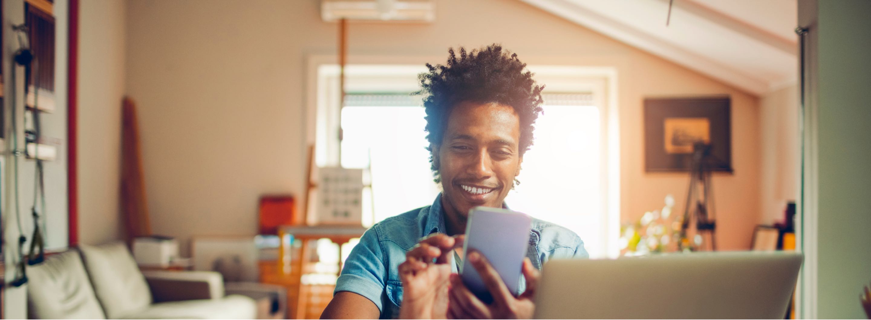 Person smiling while using a phone and laptop — check Access Wireless coverage